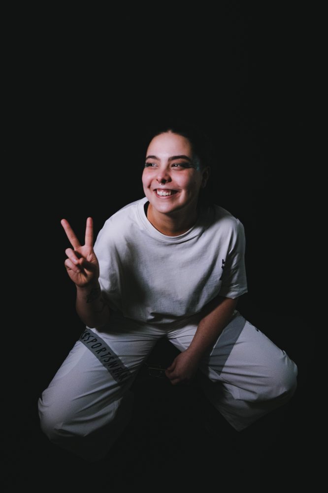 G!O portrait — smile + peace sign on black